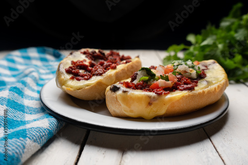 Mexican molletes with chorizo and fresh sauce on white background
