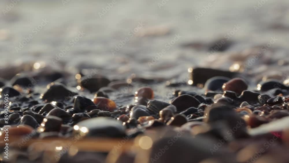 Dolly shot. Waves washing over gravel beach. Relaxing view of a stone beach washed by the sea ocean waves
