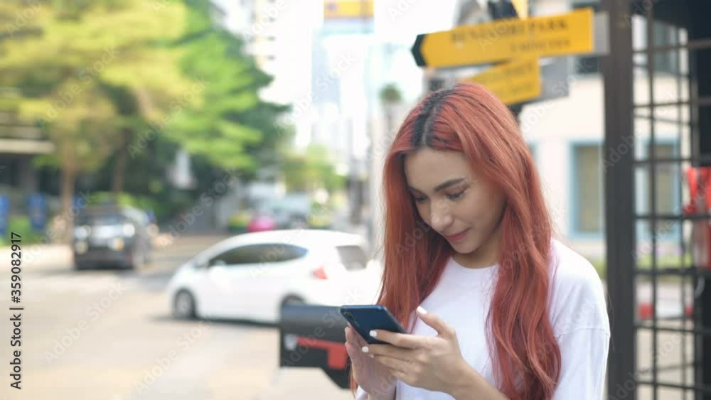 Independent concept. Asian girls playing mobile phones on the roadside. 4k Resolution.