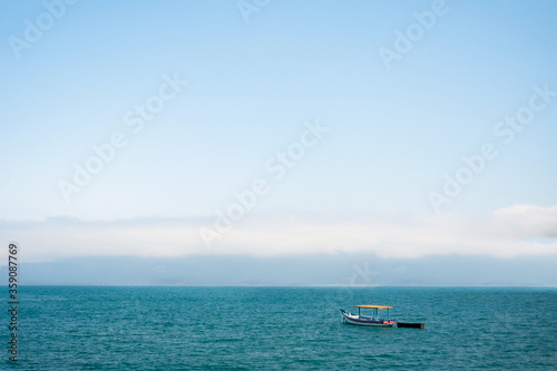 imagem panorâmica de um barco de pesca no meio do mar em um dia de céu azul no litoral norte de são paulo em Ilhabela. papel de parede.