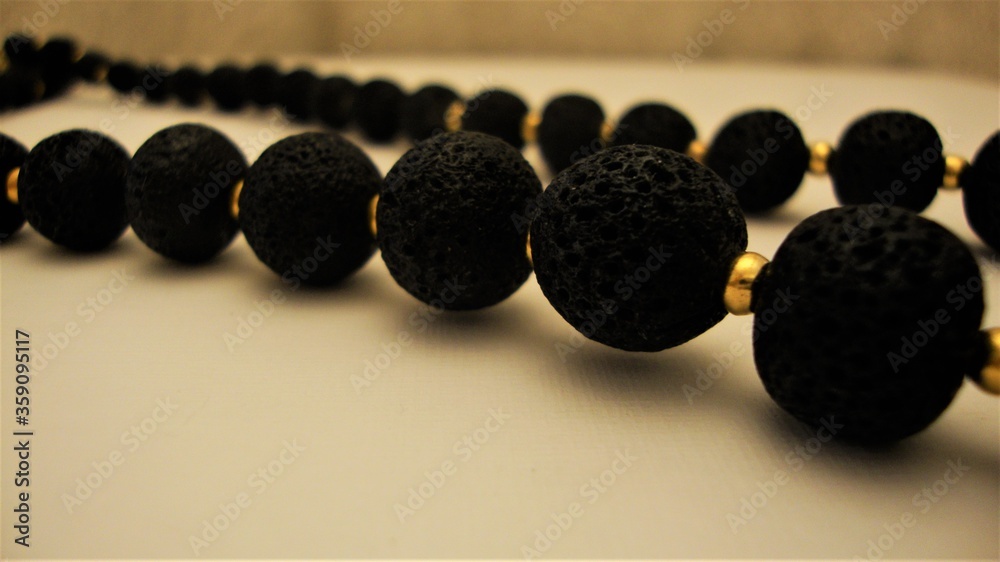 Closeup of necklace of black large beads on white surface Closeup of necklace of black large beads on white surface
