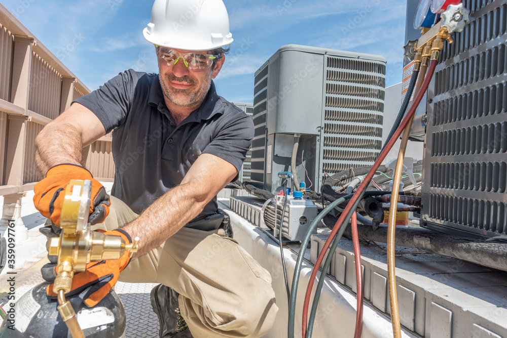 © spatesphoto - HVAC technician wearing PPE repairing a air conditioner © spatesphoto - HVAC technician wearing PPE repairing a air conditioner
