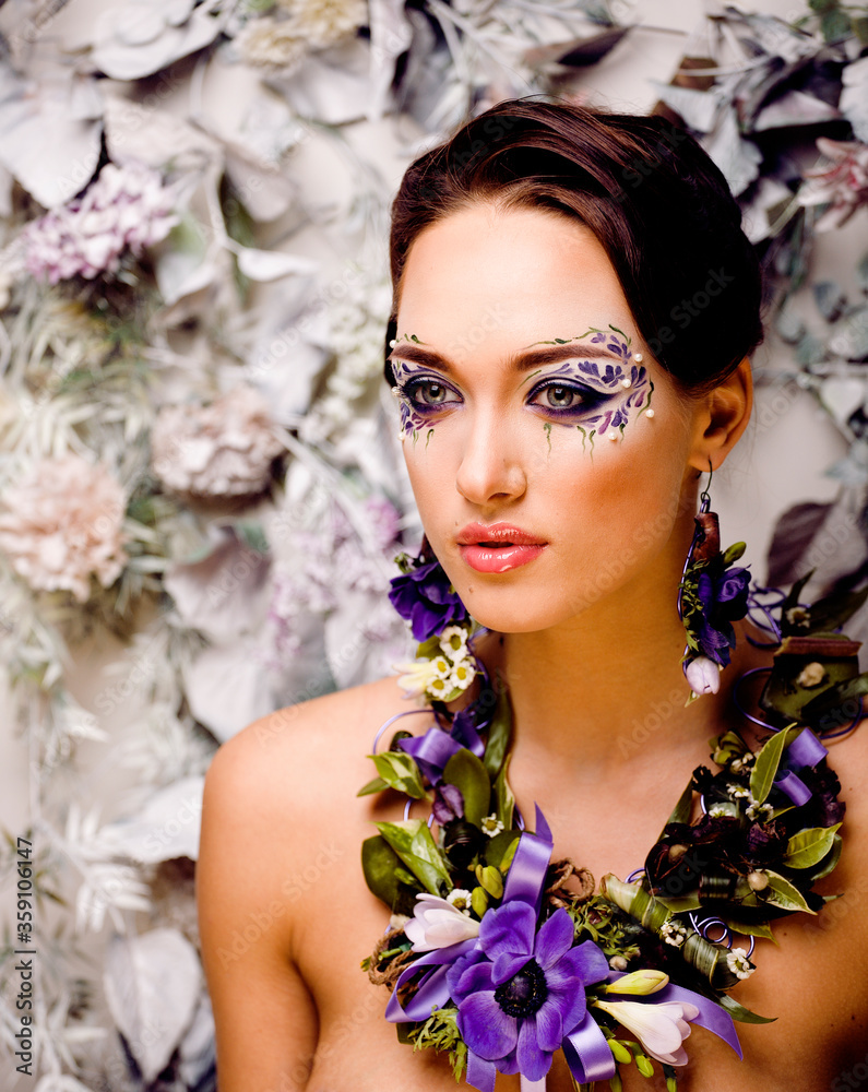 floral face art with anemone in jewelry, sensual young brunette woman in studio close up floral face art with anemone in jewelry, sensual young brunette woman in studio close up
