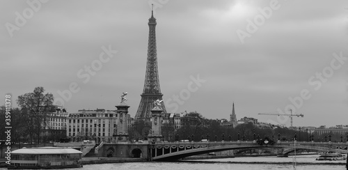 Moody panoramic cityscape with Pont Alexandre III bridge, Seine river and Eiffel Tower in Paris, France in black and white