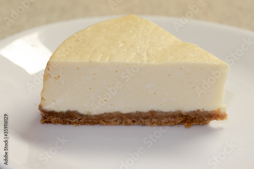 A slice of plain cheesecake on a white plate ready to be served.