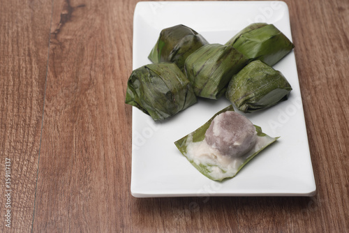 Koci the malaysian glutinous rice ball served in banana leaf on white plate over wooden table photo