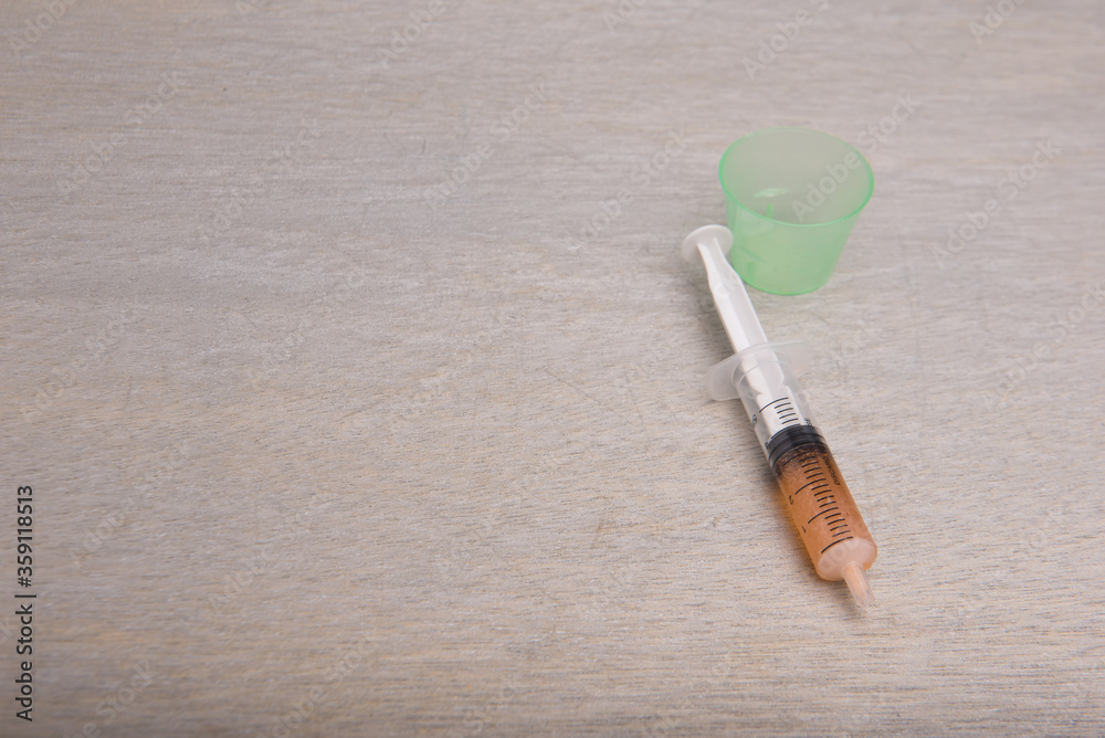 A syringe isolated over grey wooden background A syringe isolated over grey wooden background