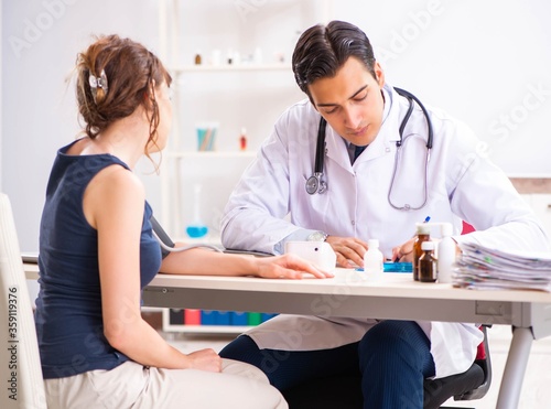 Young doctor checking woman's blood pressure