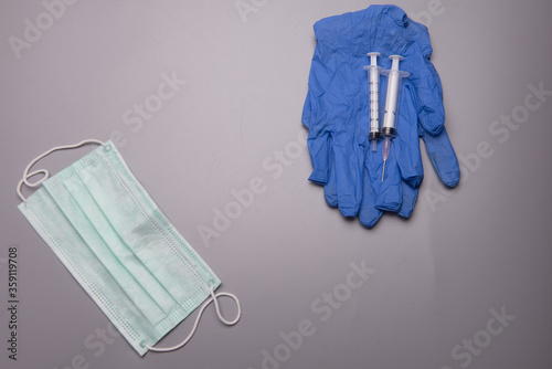 Syringes,medical latex glove and medical face mask,isolated spread over grey background,high angle or flat lay shot