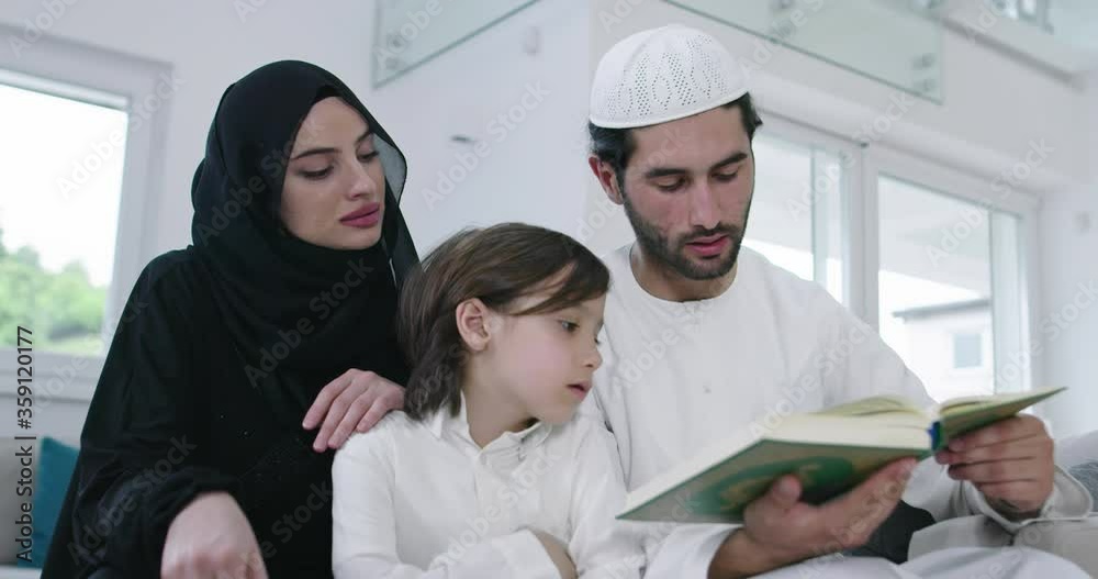 Muslim family reading Quran and praying together on the sofa