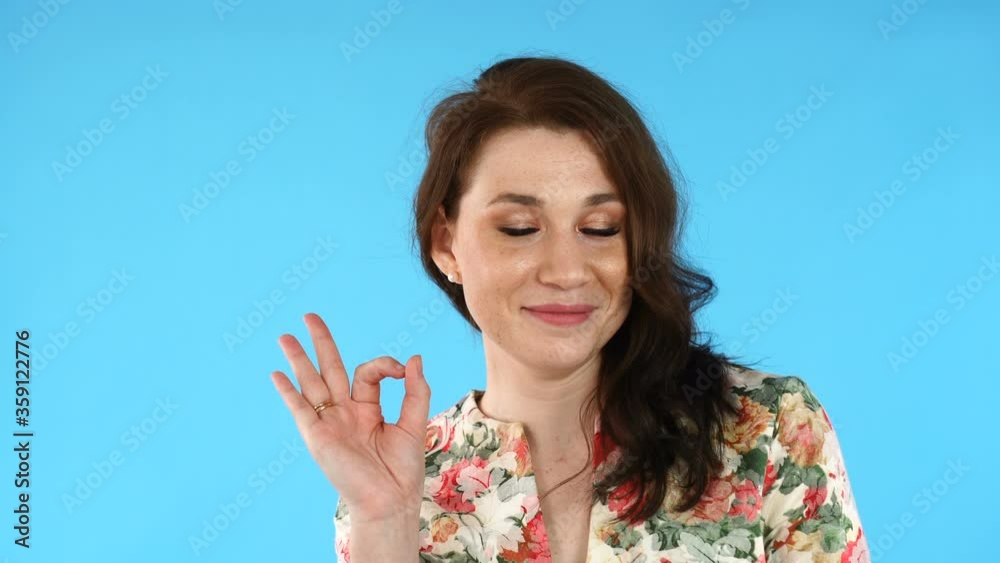 Pretty girl with stylish hairdo looking at camera and doing Ok sign with hand or okay sign with fingers Pretty girl with stylish hairdo looking at camera and doing Ok sign with hand or okay sign with fingers