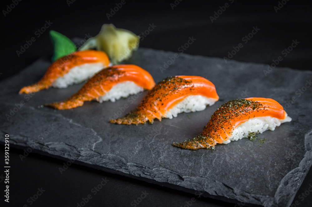 Perfect sushi, traditional Japanese cuisine. Delicious salmon kiguiri on the decorated plate, black background.