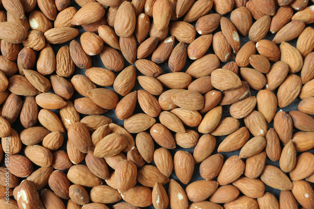 Almond nuts scattered evenly. Walnut background. Almond nuts scattered evenly. Walnut background.
