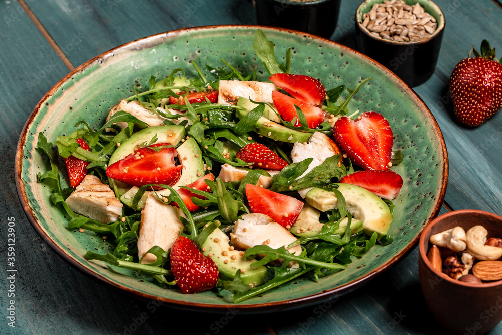 Plate with a keto diet food. strawberry salad with arugula, chicken, avocado and strawberries. Food recipe background. Close up Plate with a keto diet food. strawberry salad with arugula, chicken, avocado and strawberries. Food recipe background. Close up