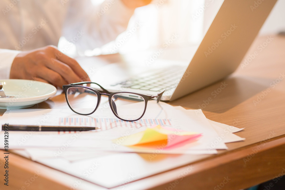 Close up glasses on Laptop,man holding cup coffee on desk work.Business concept. Close up glasses on Laptop,man holding cup coffee on desk work.Business concept.