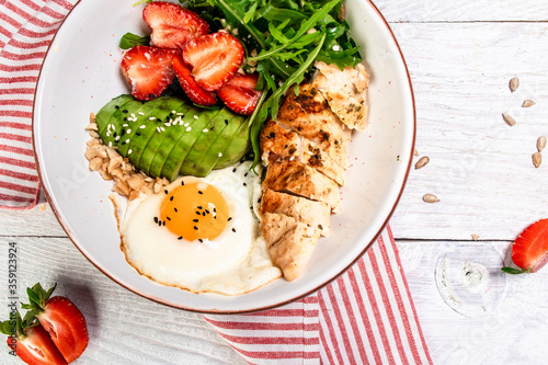 Buddha bowl with chicken  arugula and strawberries. keto diet food recipe background. Close up