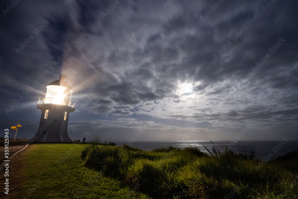 a light house at the northern most point of New Zealand at night during a storm