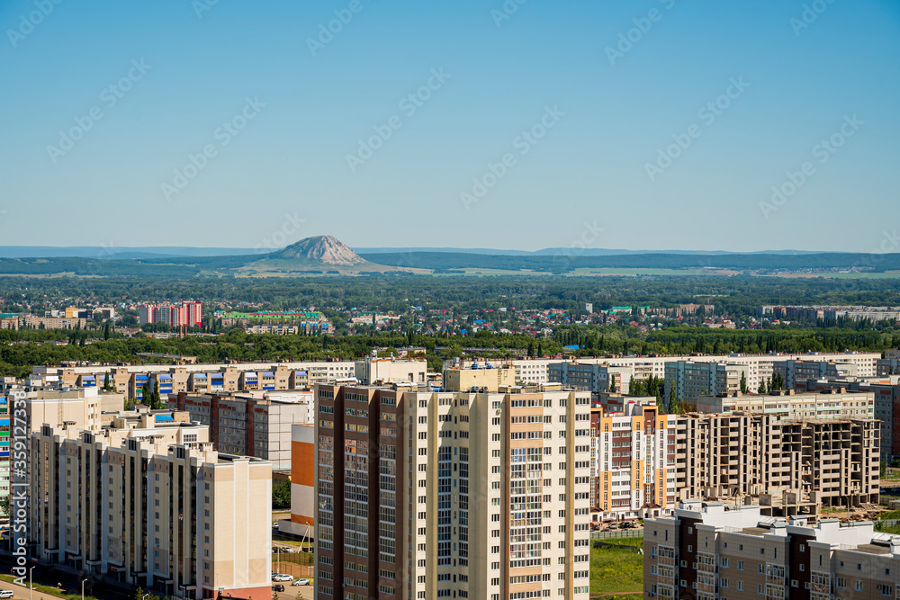 Cityscape aerial view with multi-story residential buildings and relict mountain Shihan Torah Tau in the background