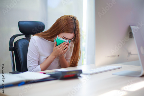 Sick Asian female working from home office is coughing and sneezing.