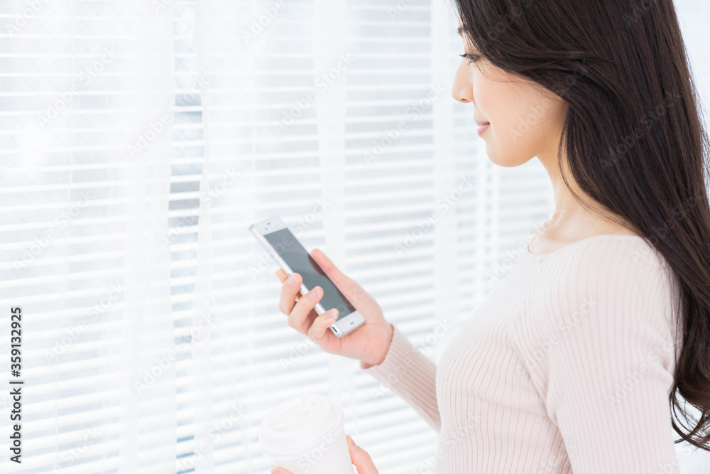 部屋でスマホを見る女性 部屋でスマホを見る女性