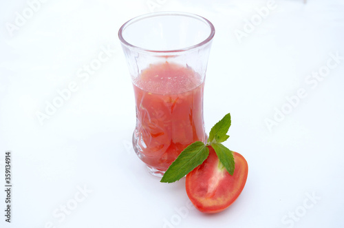 tomato juice in glass with half cutt tometo and green mint