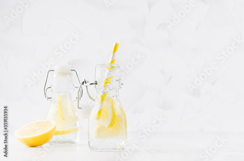 Joy bright fresh summer drinks with lemon, straw, soda water in elegant yoke bottles on soft light white wood table, copy space.