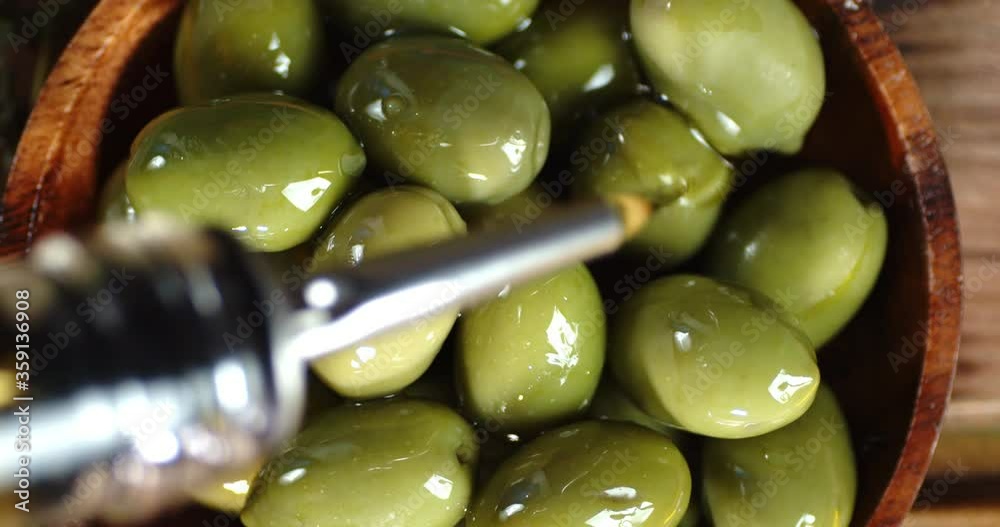 Olives in a wooden plate sprinkled with olive oil.