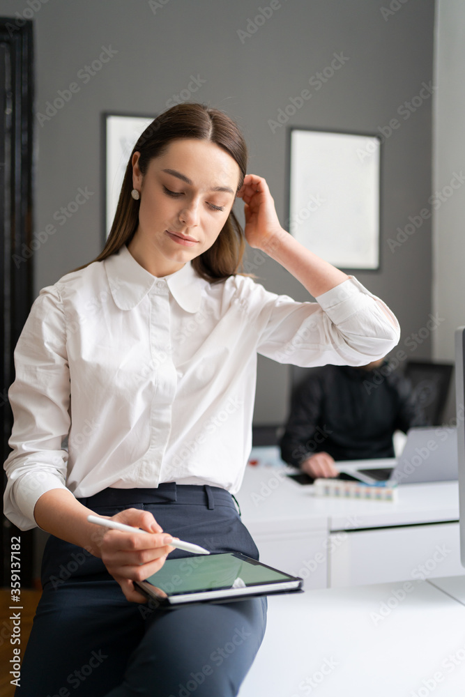 Business woman working with tablet in modern office wearing white shirt black pants Business woman working with tablet in modern office wearing white shirt black pants