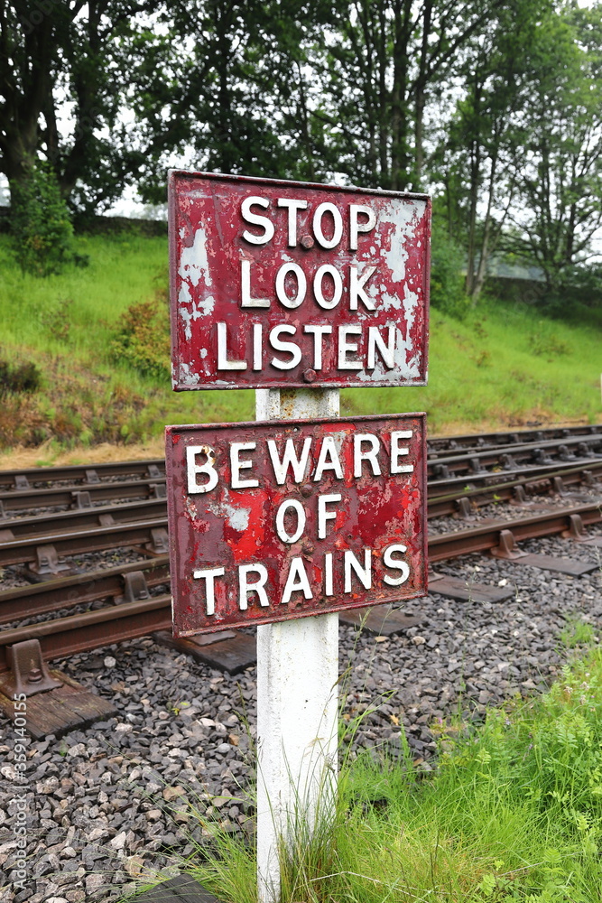 Stop Look Listen Railway Sign.  A sign warning pedestrians to stop, look and listen and beware of oncoming trains before they cross the railway line.