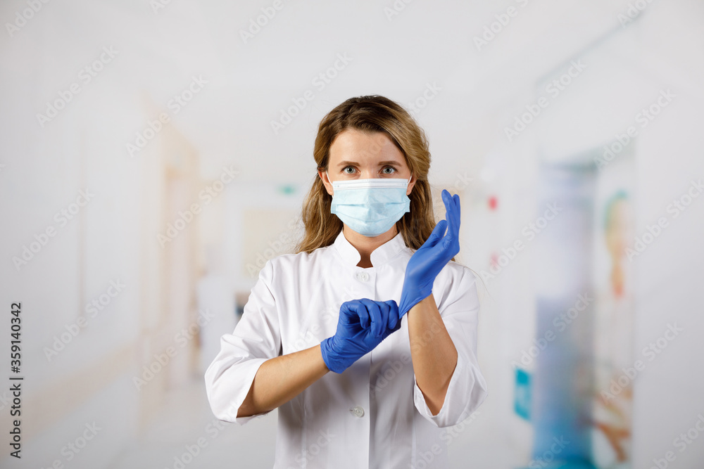 Doctor woman surgeon specialist in sterile clothing putting on surgical gloves.