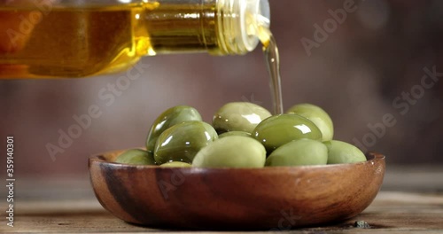Olives in a plate poured of olive oil from the bottle.