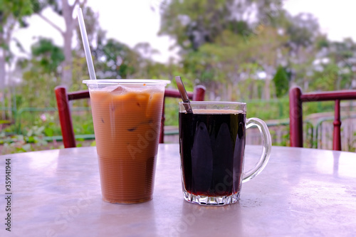 Photography Popular local beverages of iced tea with milk and hot black coffee, commonly known as Teh Peng and Kopi-O, in a coffeeshop overlooking a park