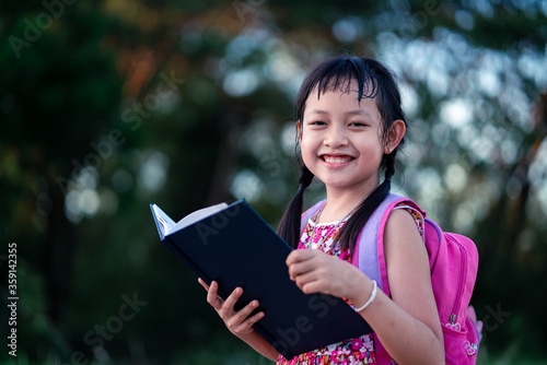 Smile little school girl reading book with backpack.Back to school concept