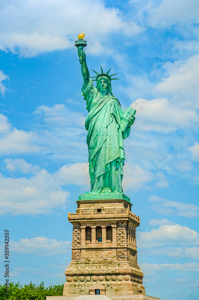 Fototapeta premium USA: The outdoor Statue of Liberty on a background of blue sky with white clouds on Liberty Island in New York, USA