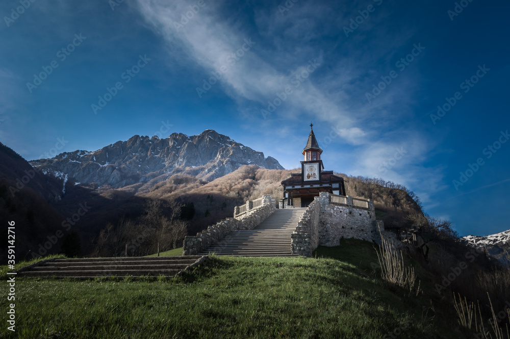 Memorial Church of the Holy Spirit in Javorca in Slovenia built by Austro-Hungarian soldiers. Famous picturesque stairs, Alps mountain range and blue sky in background. Low angle, wide shot