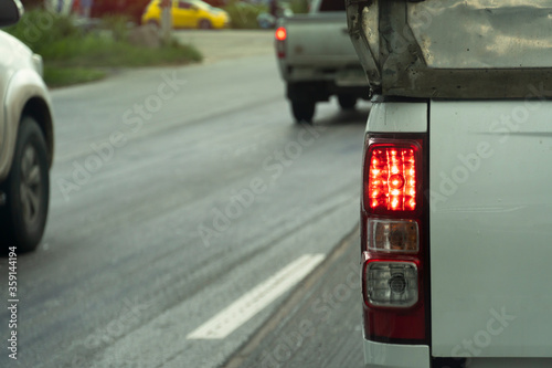 Back view of rear side white pick up car drive on the road. with open brake light. © thongchainak