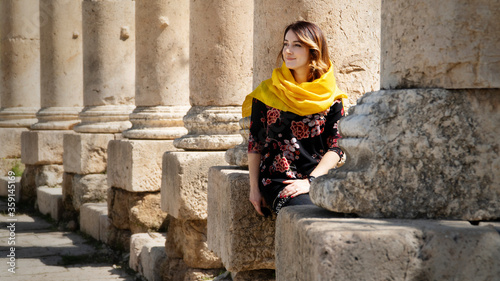 Canvas Print Young woman sitting in the columns of the Oval Plaza of Jerash, ancient Roman city in Jordan