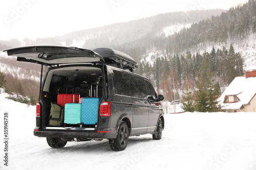 Black car with luggage in trunk on snowy road. Winter vacation