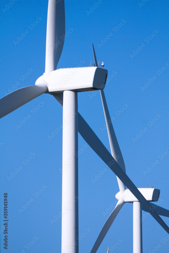 Pico Gallo, Tineo, Asturias. Back view of blades, rotor hub and nacelle of two wind mills and blue sky in the background. Pico Gallo, Tineo, Asturias. Back view of blades, rotor hub and nacelle of two wind mills and blue sky in the background.