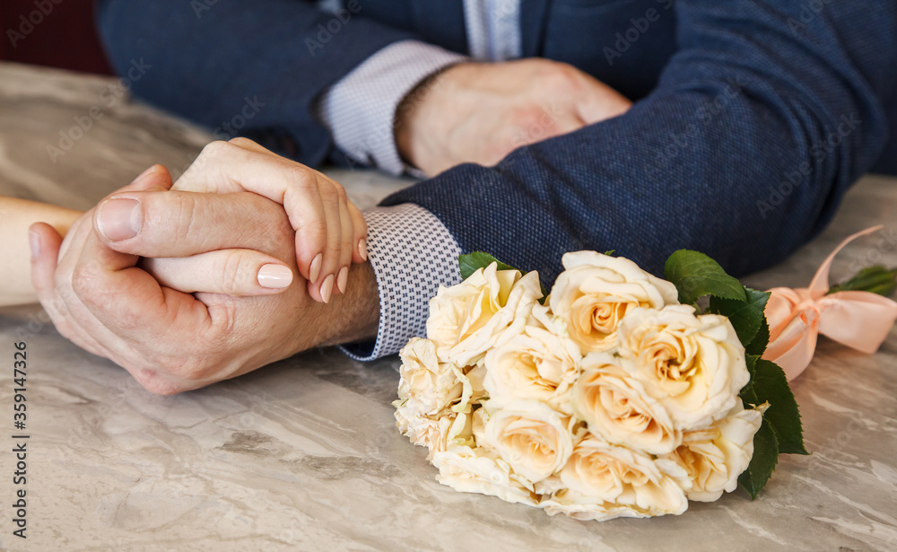 newlyweds hold hands next to a wedding bouquet
