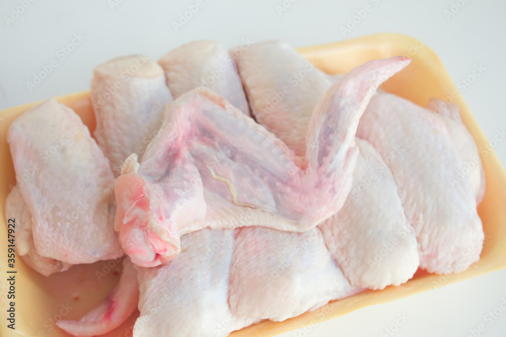 Chilled chicken wings in a yellow tray, fresh meat from the store on a white table. High protein in chicken