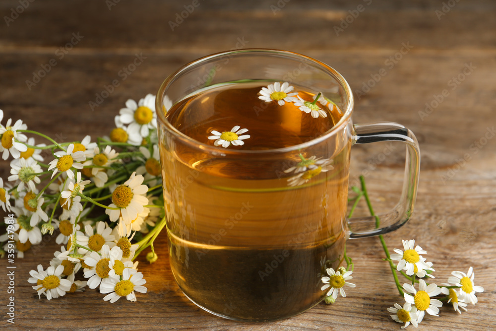 Cup of tea and chamomile flowers on wooden table Cup of tea and chamomile flowers on wooden table