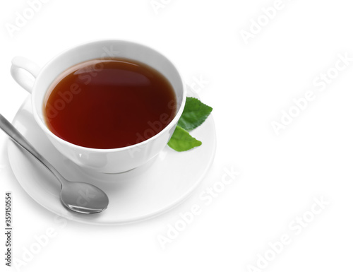 Cup of aromatic black tea, spoon and green leaves on white background