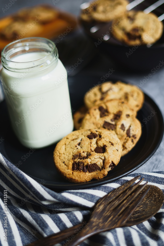 Chocolate chips cookie and milk on a wooden plate. Chocolate chips cookie and milk on a wooden plate.