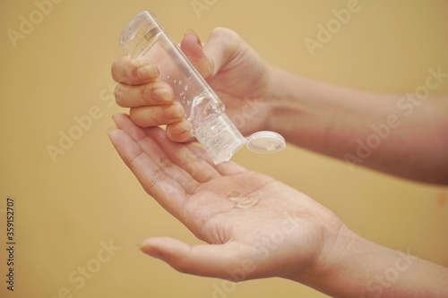 Close up of a hand using hand sanitizer with yellow backgorund.