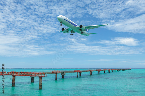 Landing airplane on emelardgreen ocean in summer photo