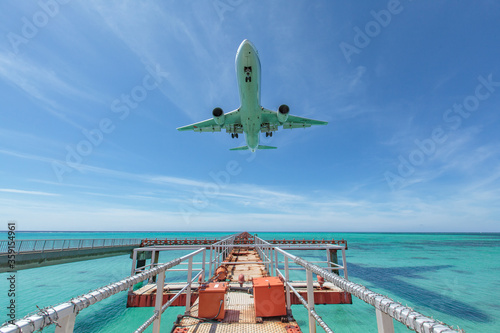 Landing airplane on emelardgreen ocean in summer photo