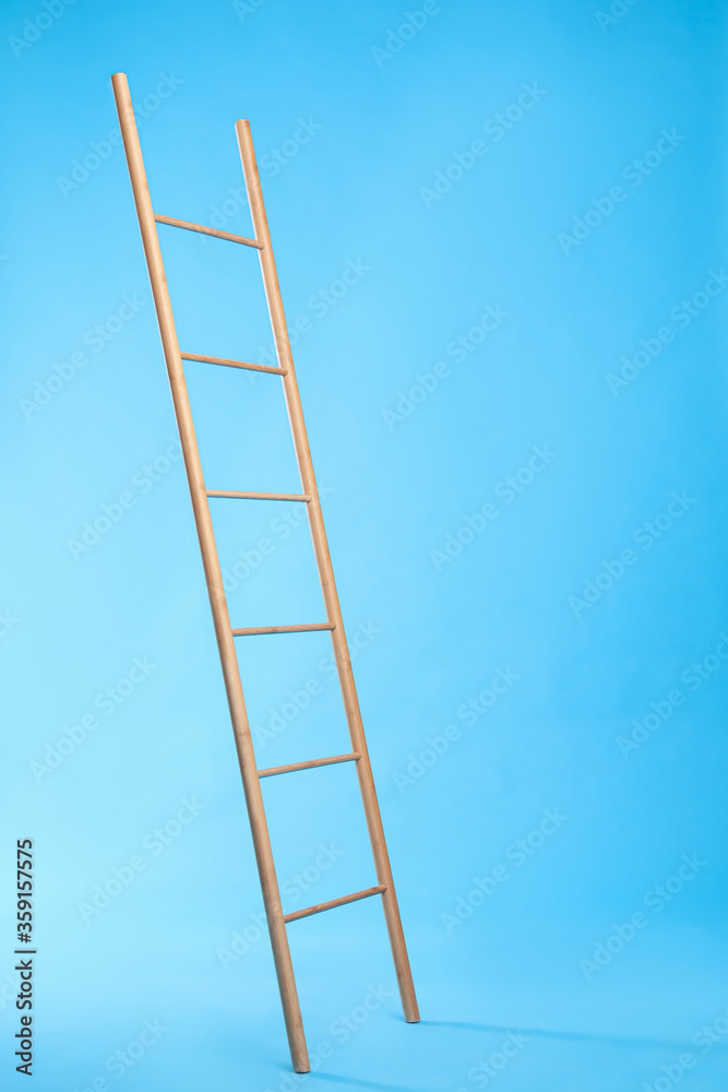 Modern wooden ladder on light blue background Modern wooden ladder on light blue background