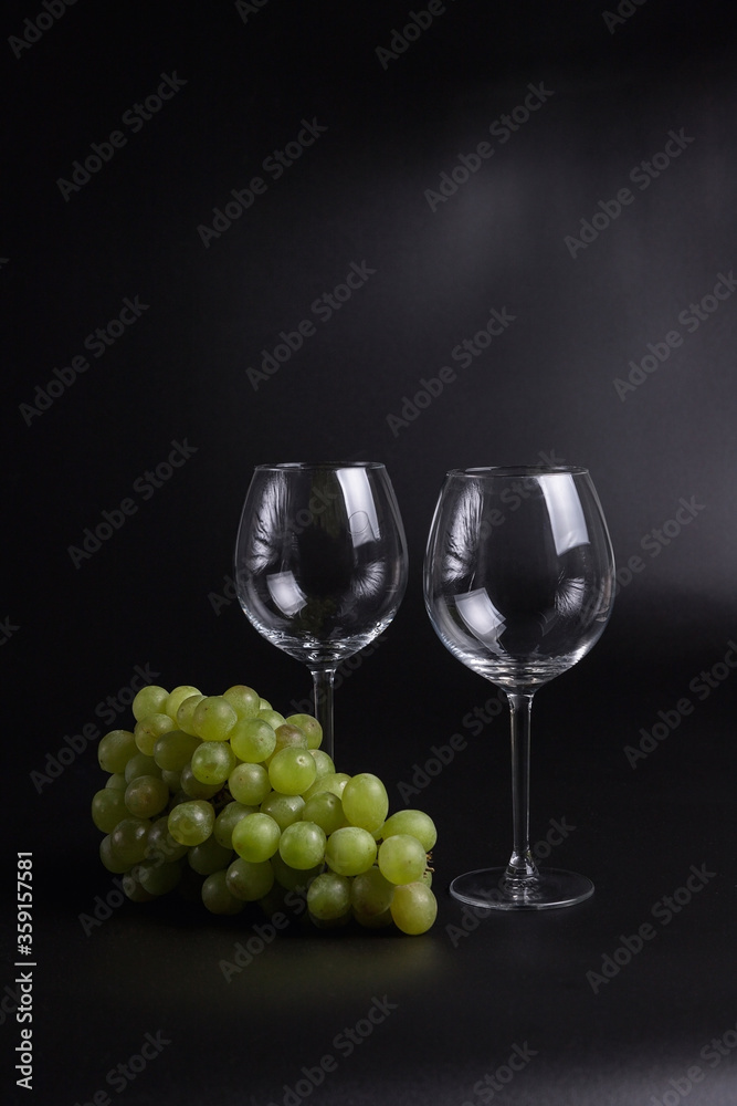 Still life on a black background. A glass wine glass and grape vine. Still life on a black background. A glass wine glass and grape vine.