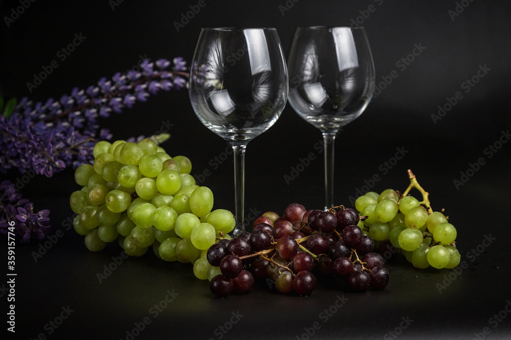 Still life on a black background. A glass wine glass and grape vine. Lupins on the black. Still life on a black background. A glass wine glass and grape vine. Lupins on the black.